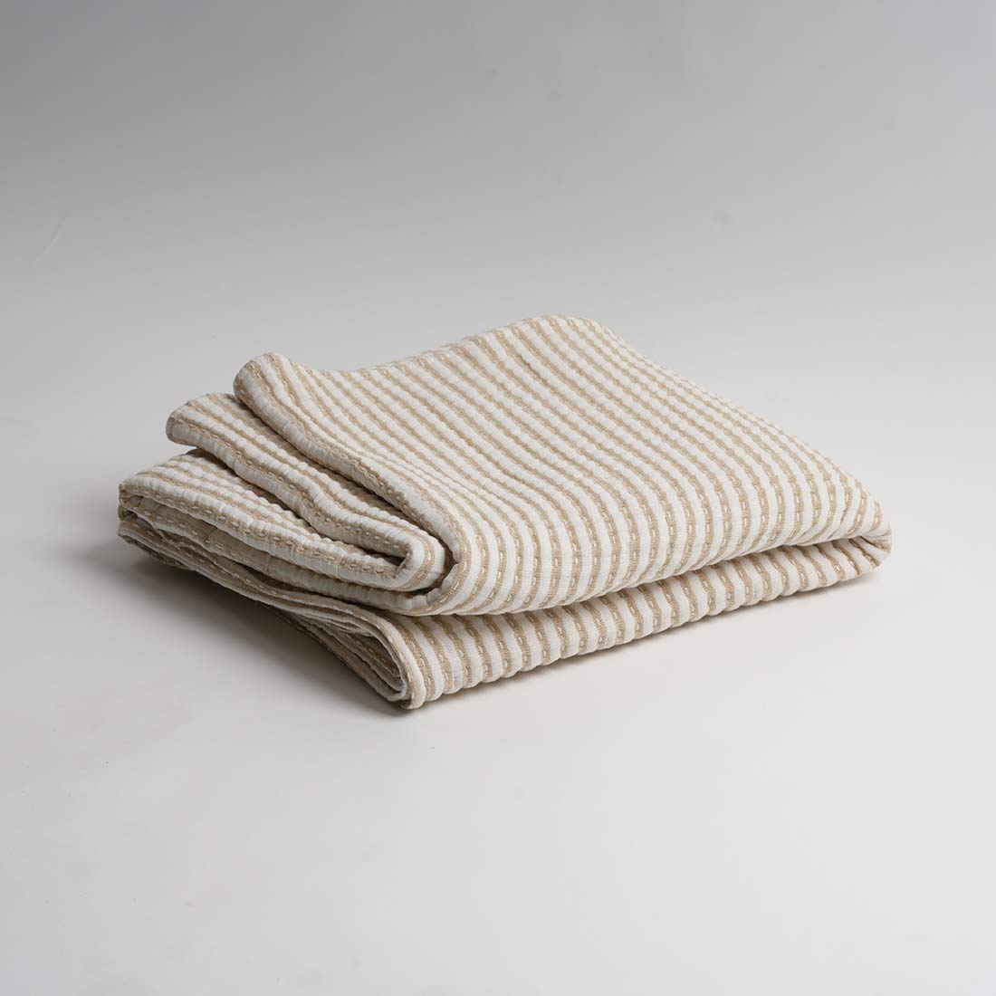 Folded striped blanket on a light gray background