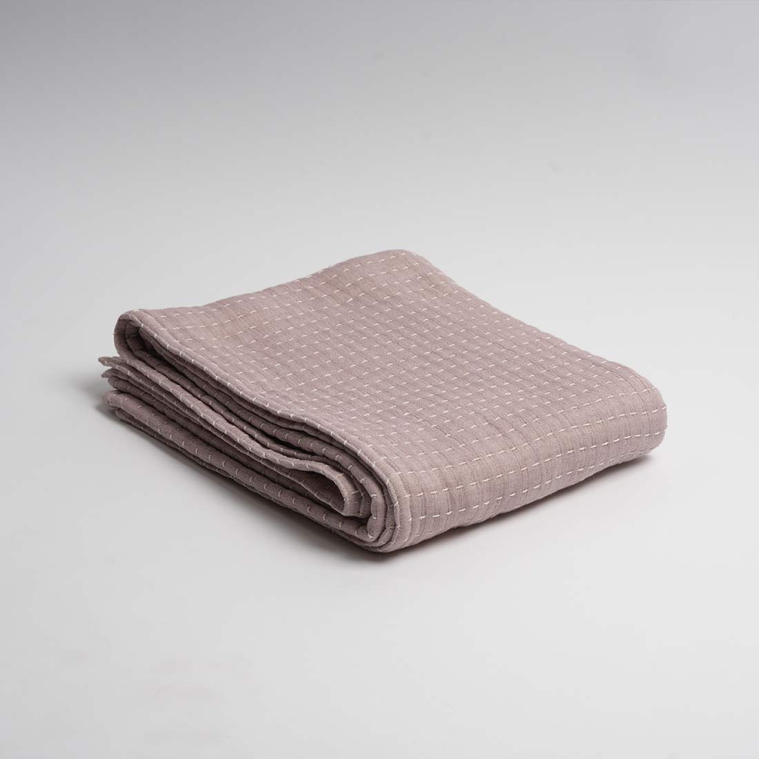 Folded pink textured throw on a light gray background