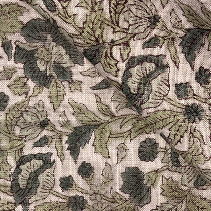 Close-up of a floral patterned fabric with green and black leaves on a beige background