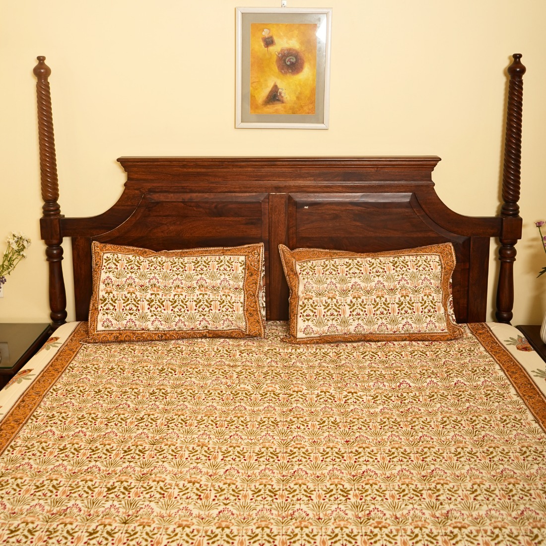 Bed with wooden headboard and patterned bedding, framed picture on wall.