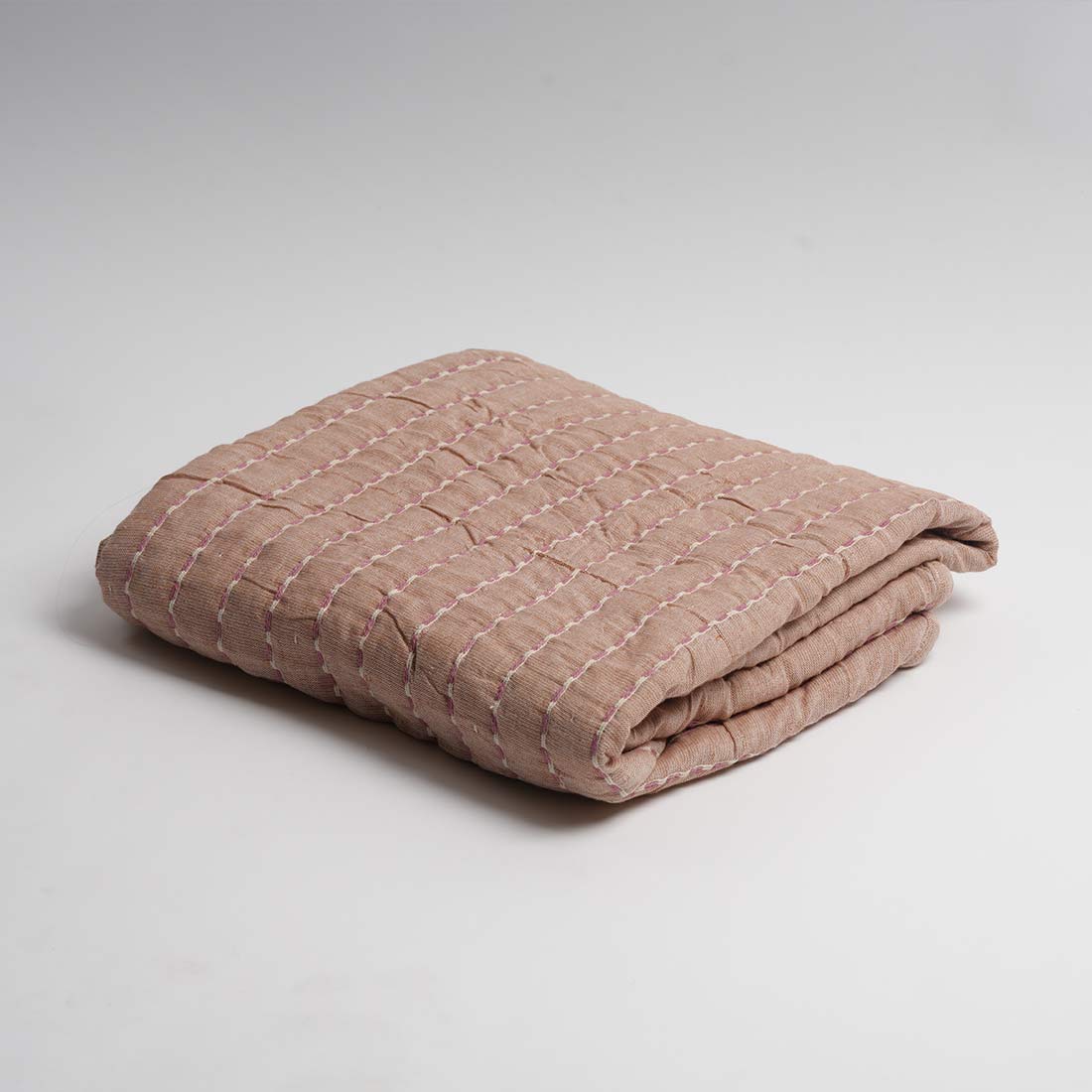 Folded beige throw on a light gray background