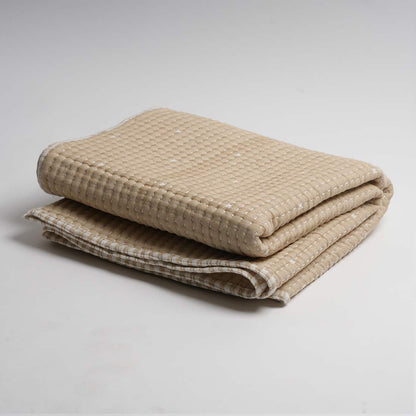 Folded beige throw on a light gray background