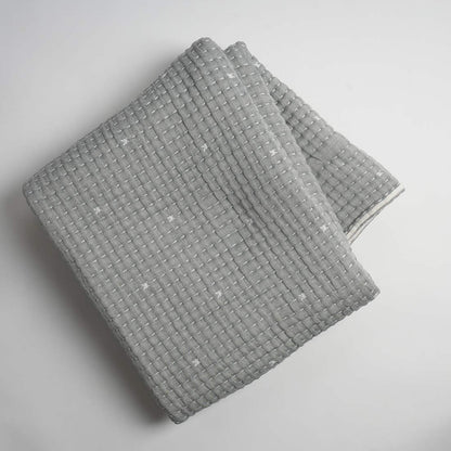 Folded gray textured throw on a light gray background