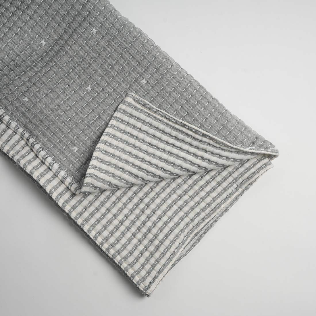 Gray throw with a striped pattern on a light gray background