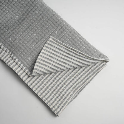 Gray throw with a striped pattern on a light gray background