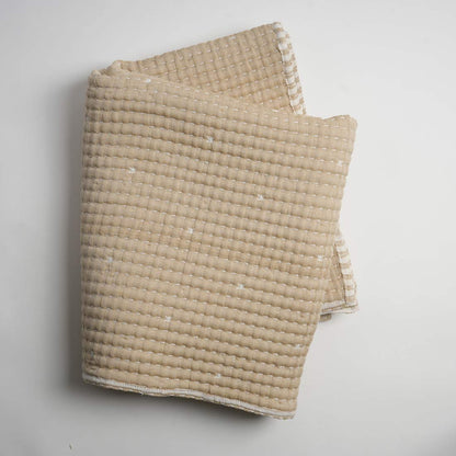 Beige textured blanket on a light gray background