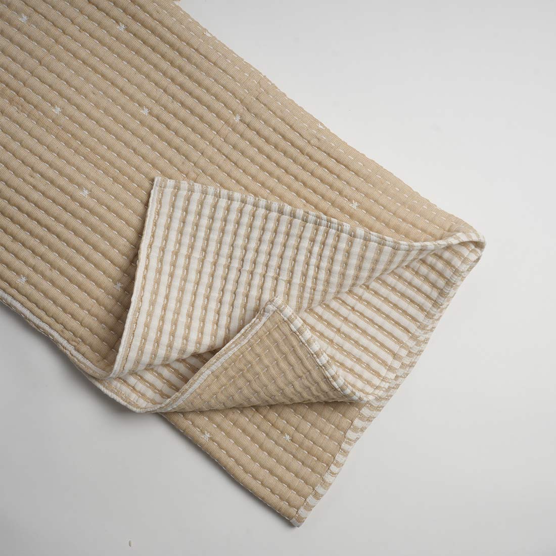 Folded beige throw with textured pattern on a light gray background