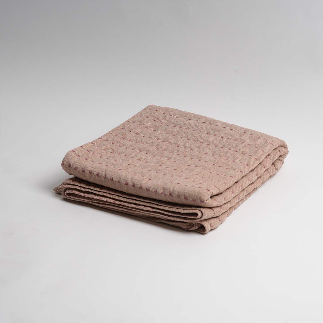 Folded beige throw on a light gray background