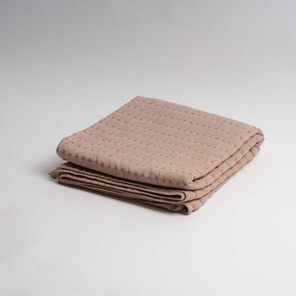 Folded beige throw on a light gray background