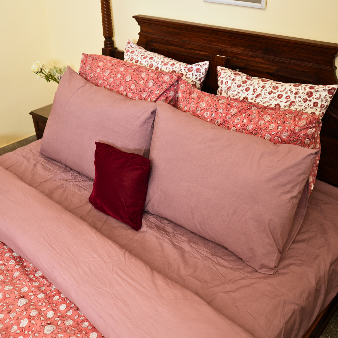 Bed with pink and red floral bedding and pillows.