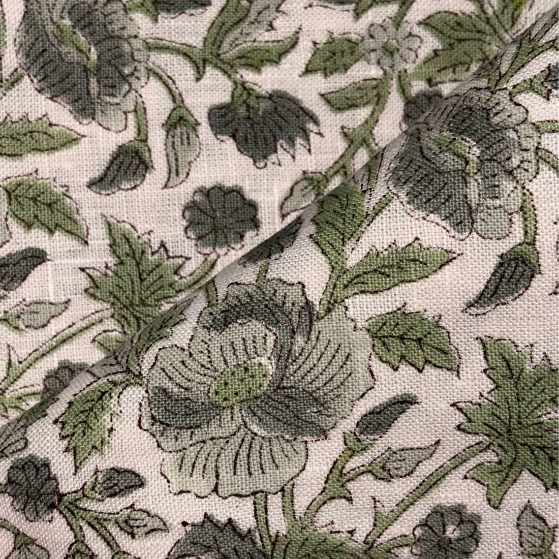 Close-up of floral fabric pattern with green flowers and leaves on a grey background
