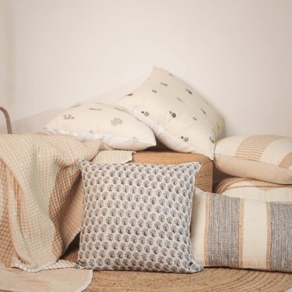 Collection of patterned pillows on a wooden surface with a neutral background