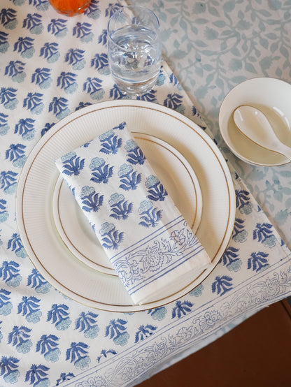 Table setting with blue and white patterned tablecloth, plates, and napkin.