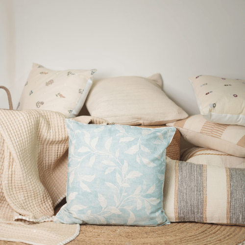 Decorative pillows on a sofa with a light blue floral pillow in the foreground