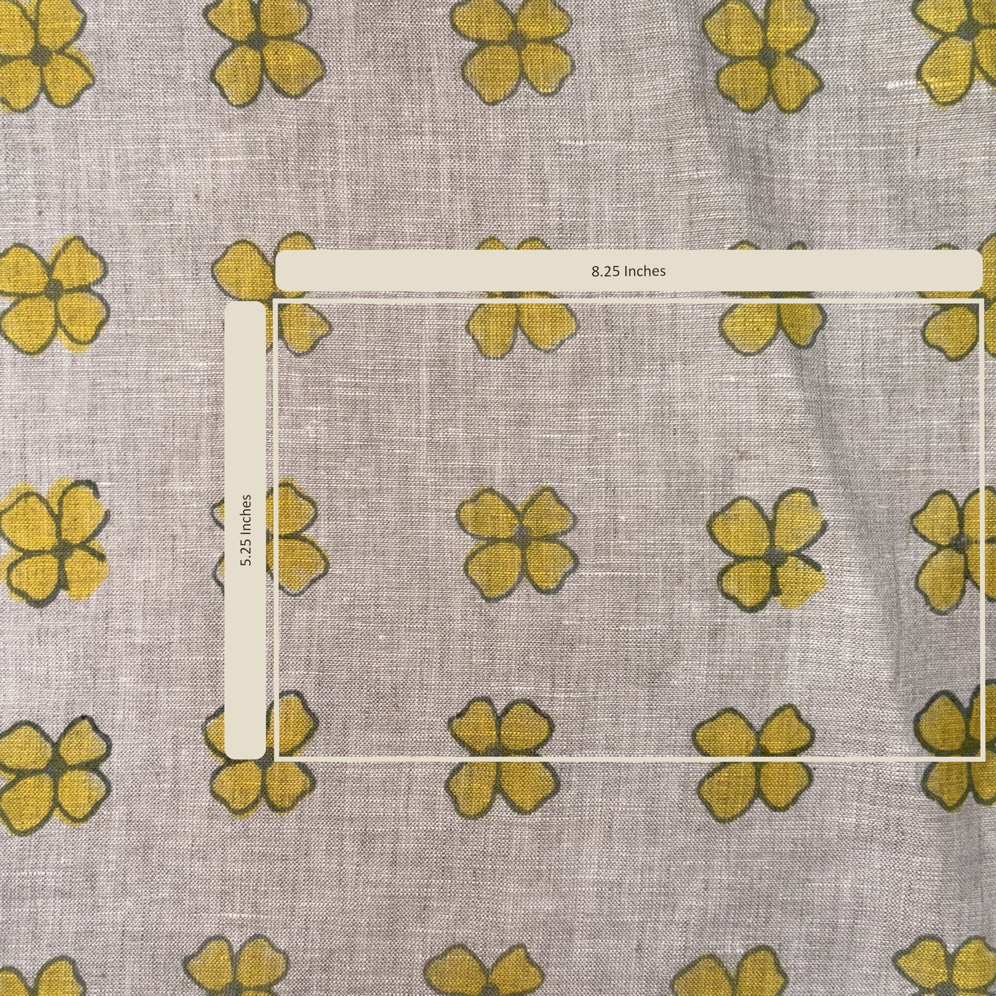 Fabric with yellow flower pattern and a ruler for scale on a gray background