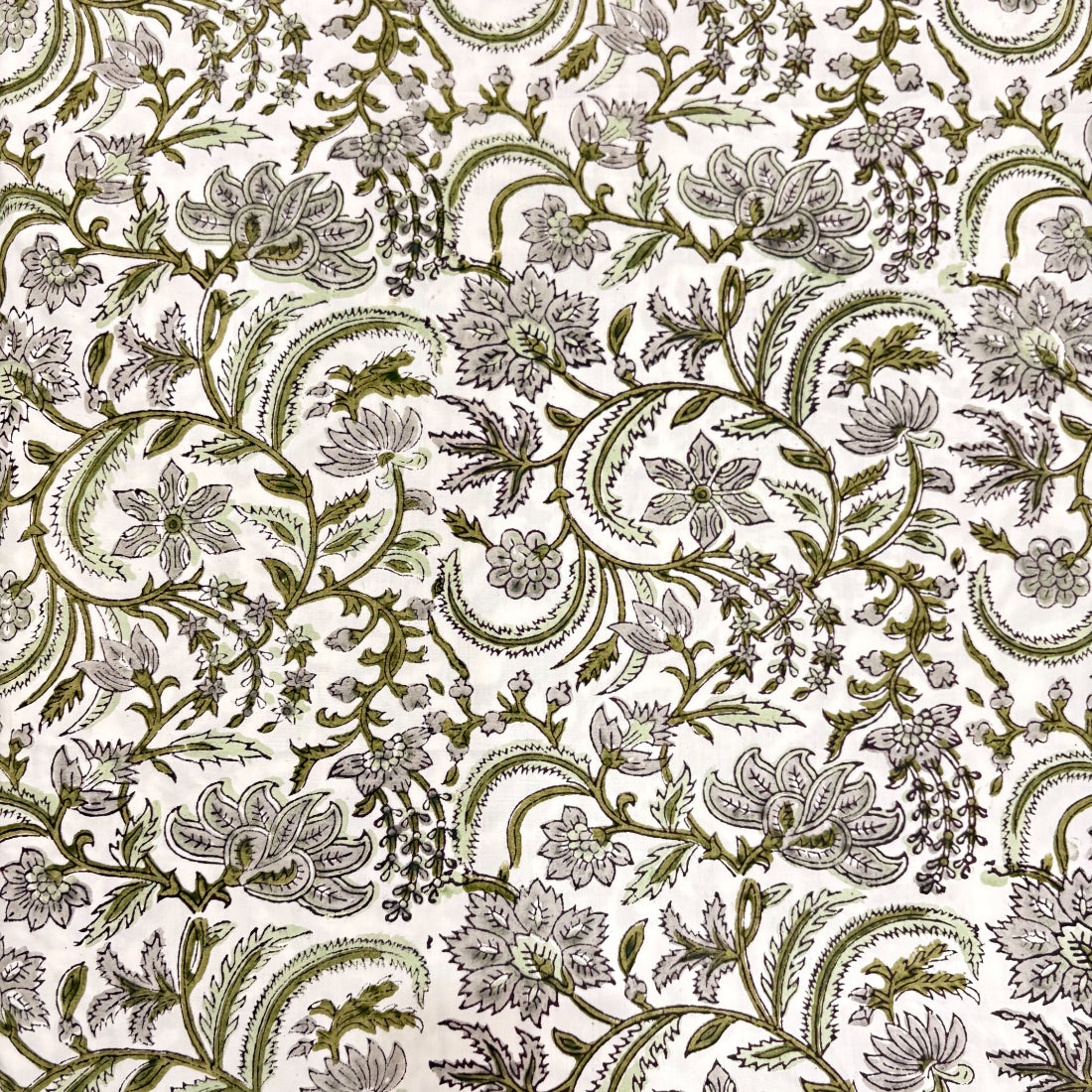 Floral and paisley patterned fabric in green on a white background