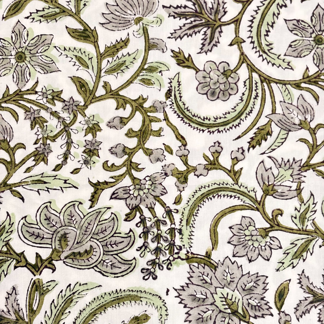 Close-up of a fabric with intricate paisley pattern in green on a white background