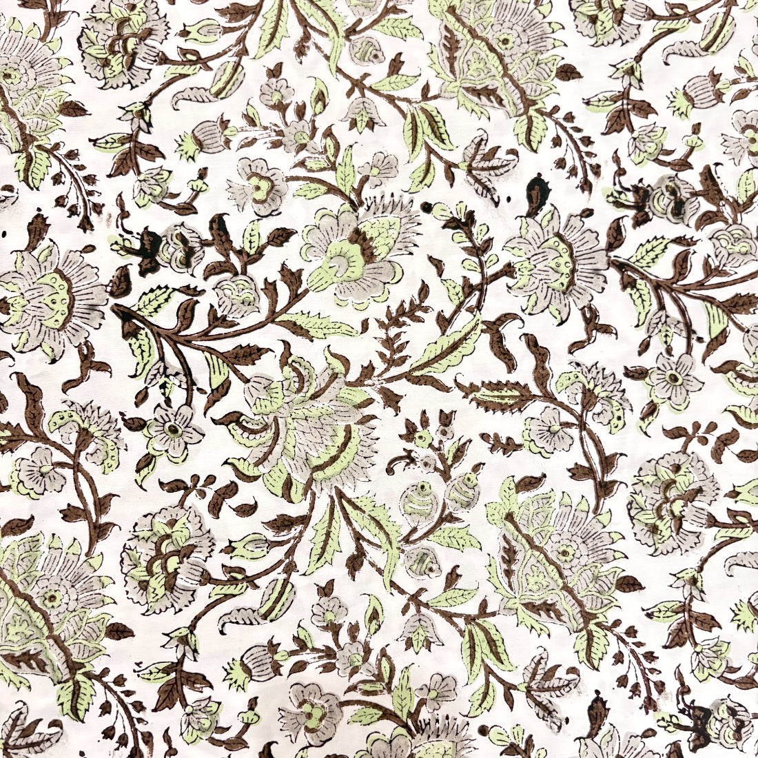 Close-up of a fabric pattern in green and brown on a white background
