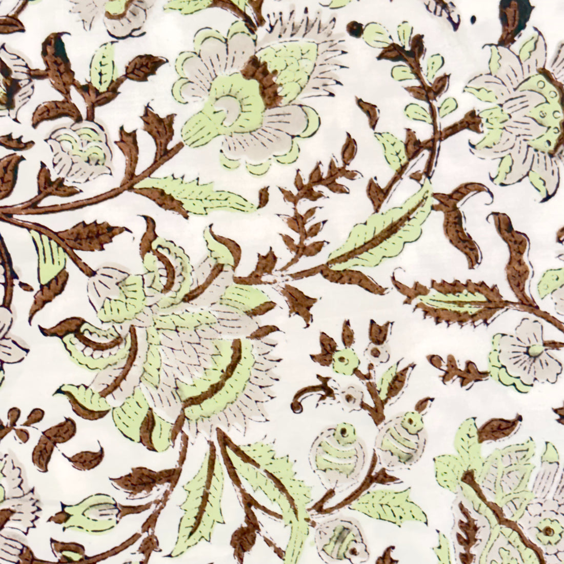 Close-up of a floral and leaf patterned fabric in green and brown on a white background