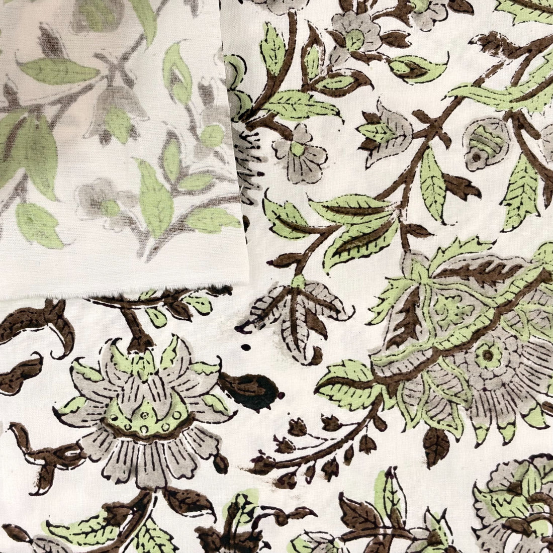 Close-up of a floral and leaf patterned fabric in green and brown on a white background