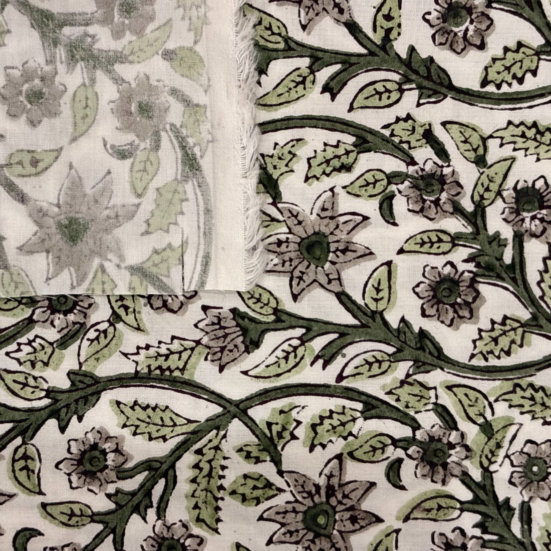 Close-up of a floral and leaf patterned fabric in green on a white background