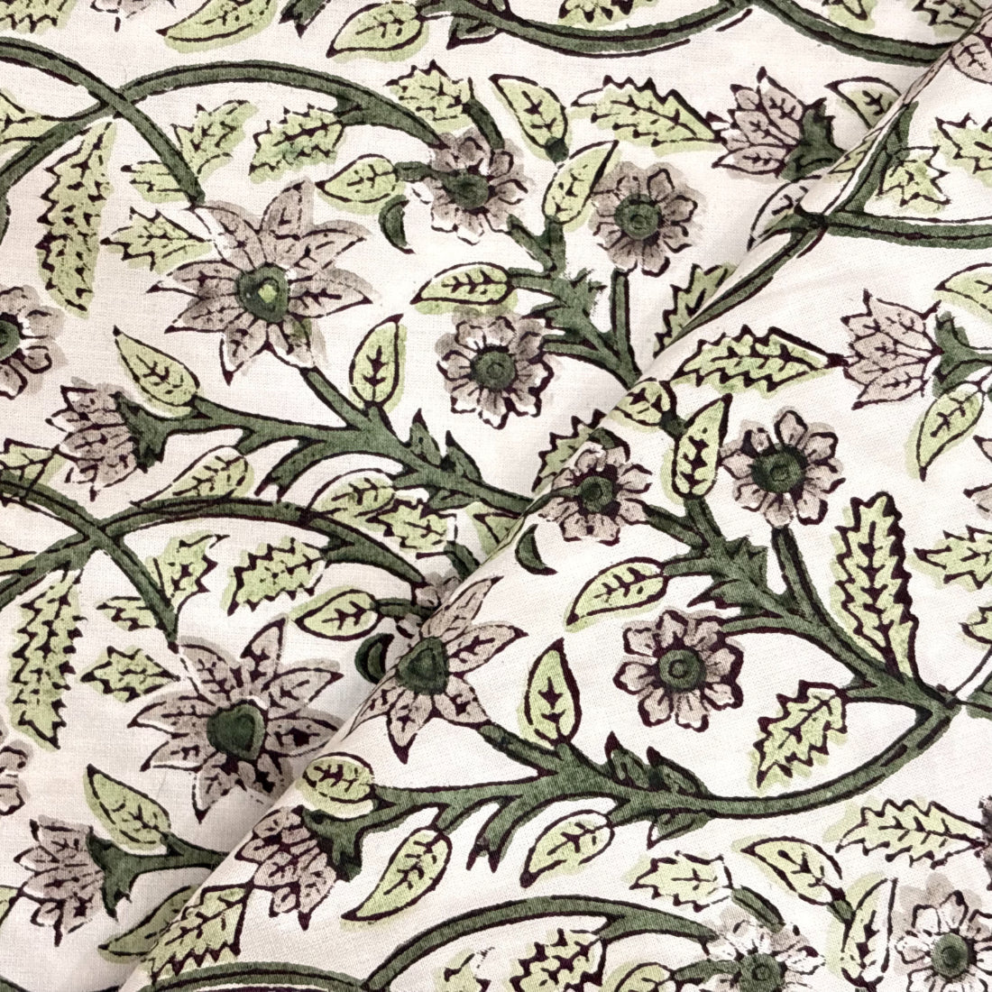 Close-up of a floral and leaf patterned fabric in green on a white background