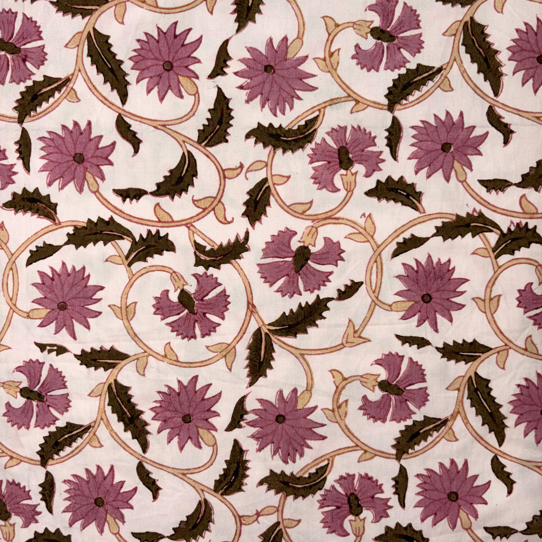 A close-up of a fabric or wallpaper pattern featuring repeating mauve-pink flowers and dark brown leaves on a warm off-white background, woven with tan scrolling vines.