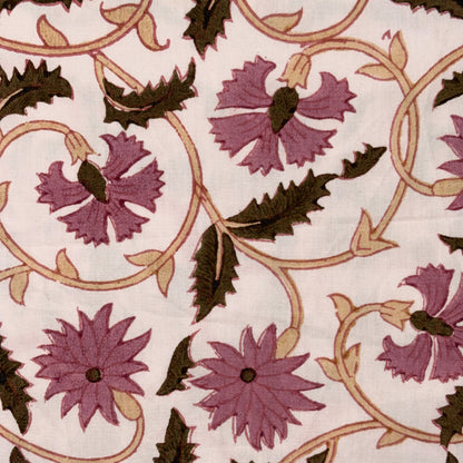 A close-up of a fabric or wallpaper pattern featuring purple flowers, dark green leaves, and tan scrolling vines on a light cream background.