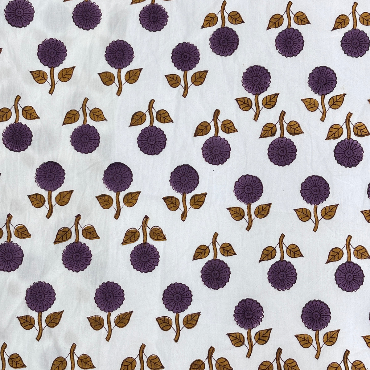 White fabric with a repeating block-print pattern of purple flowers and brown leaves.