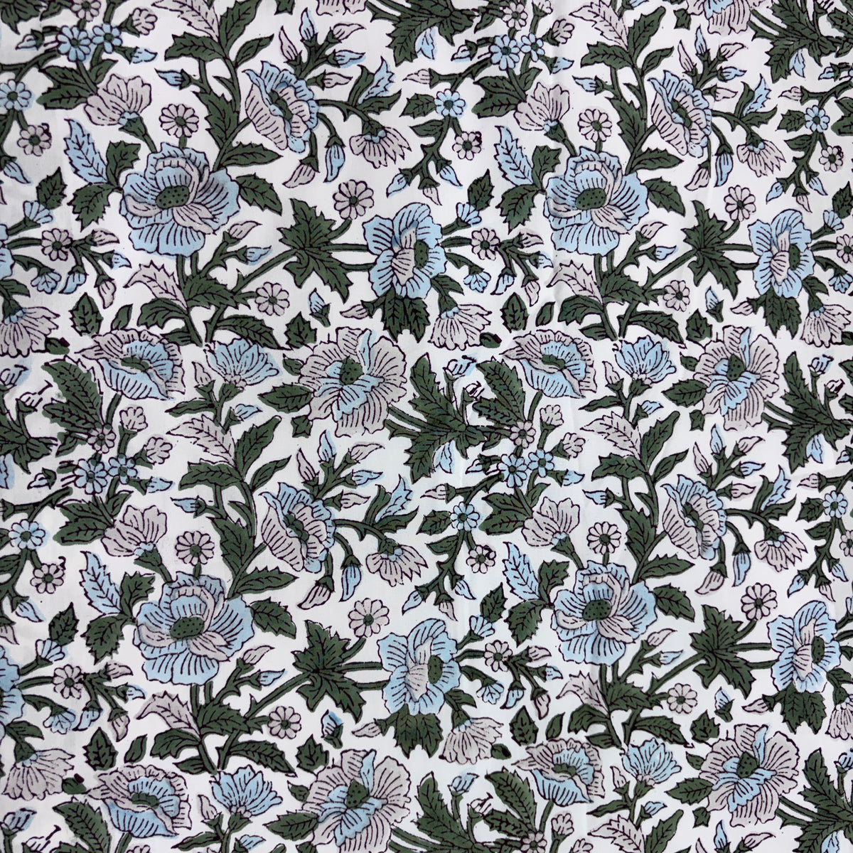 A close-up of a floral fabric pattern featuring light blue and lavender flowers with dark green leaves on a white background.
