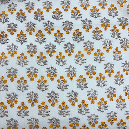 White fabric with a repeating block-printed pattern of mustard yellow flowers and gray-green leaves.
