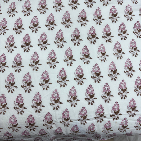 White cotton fabric with a repeating block-printed floral pattern in pink and brown.