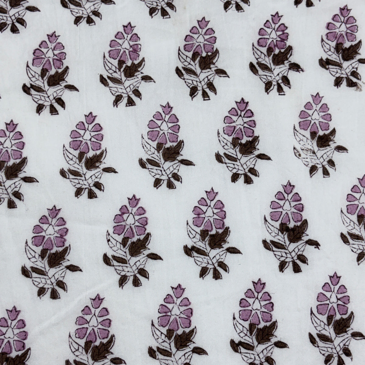 White fabric with a repeating block-print floral pattern in purple and dark brown.