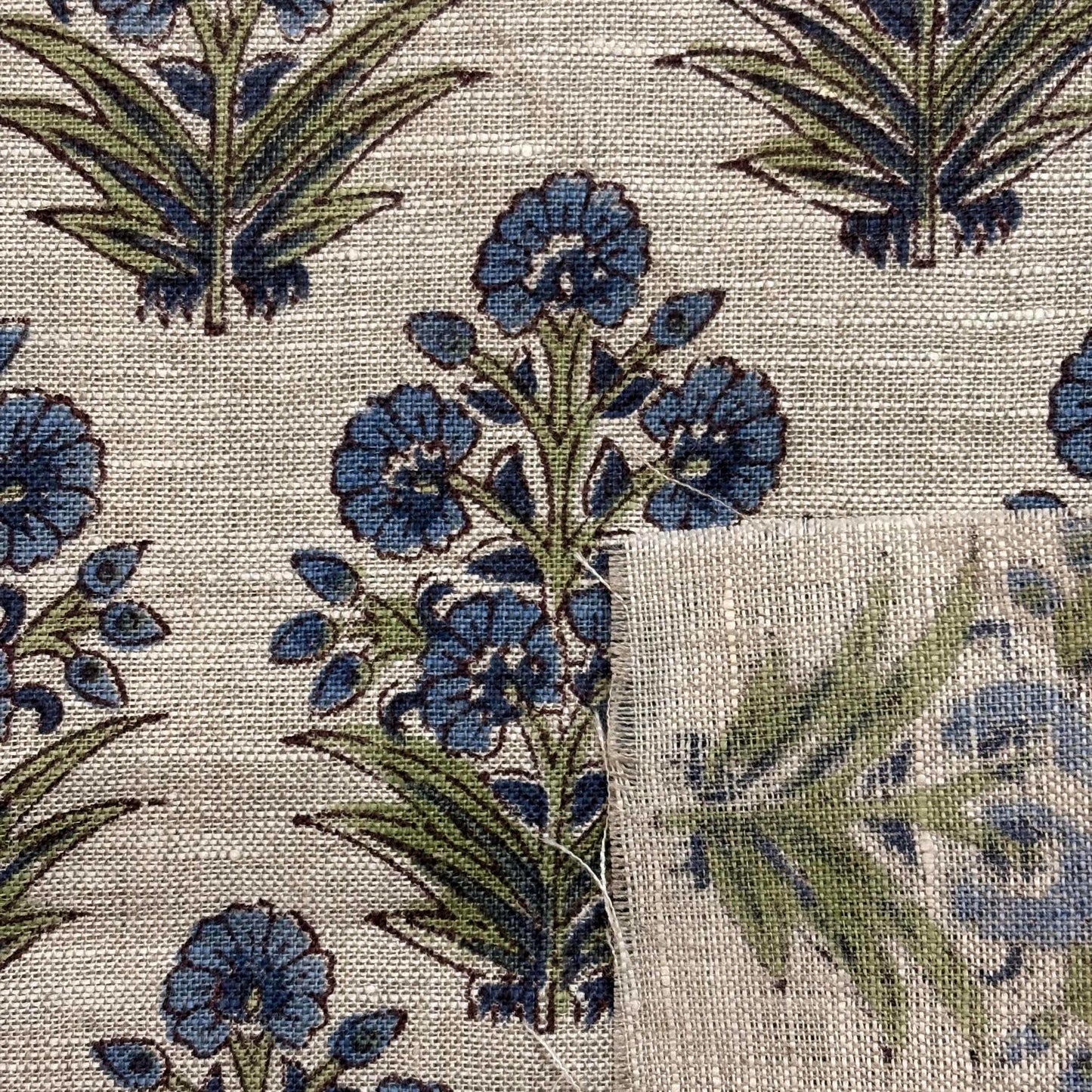 Close-up of floral fabric pattern with blue flowers and green leaves on a grey background