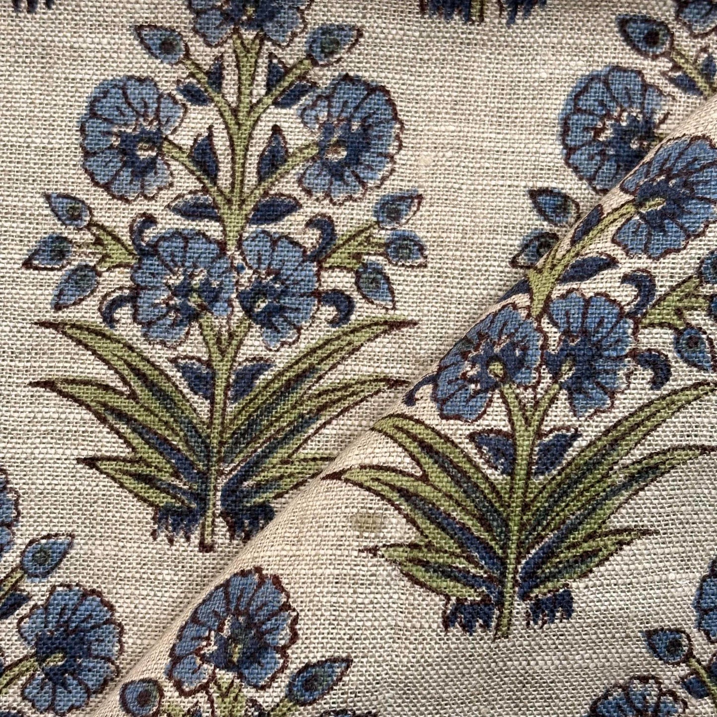 Close-up of floral patterned fabric with blue flowers and green leaves.