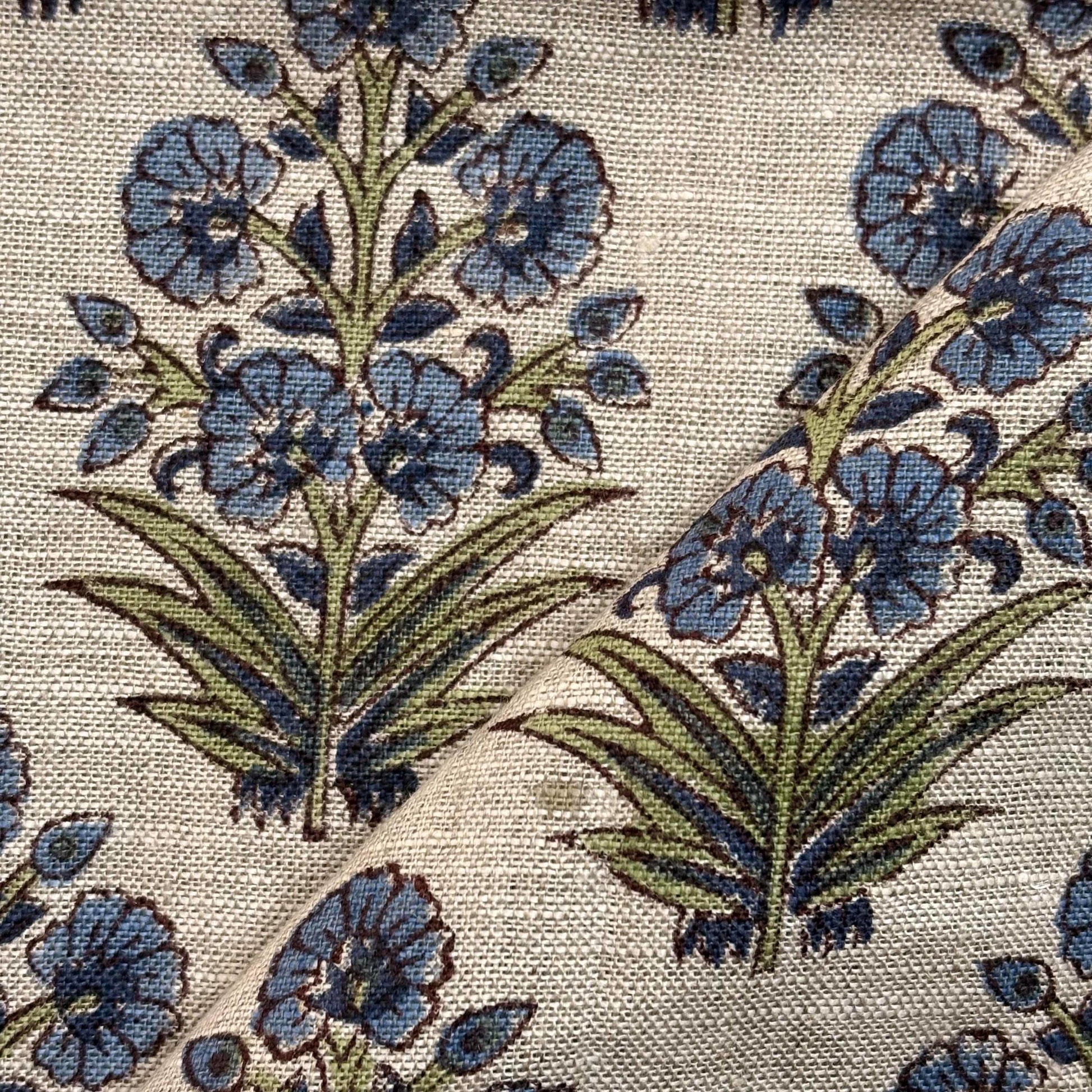 Close-up of floral patterned fabric with blue flowers and green leaves.