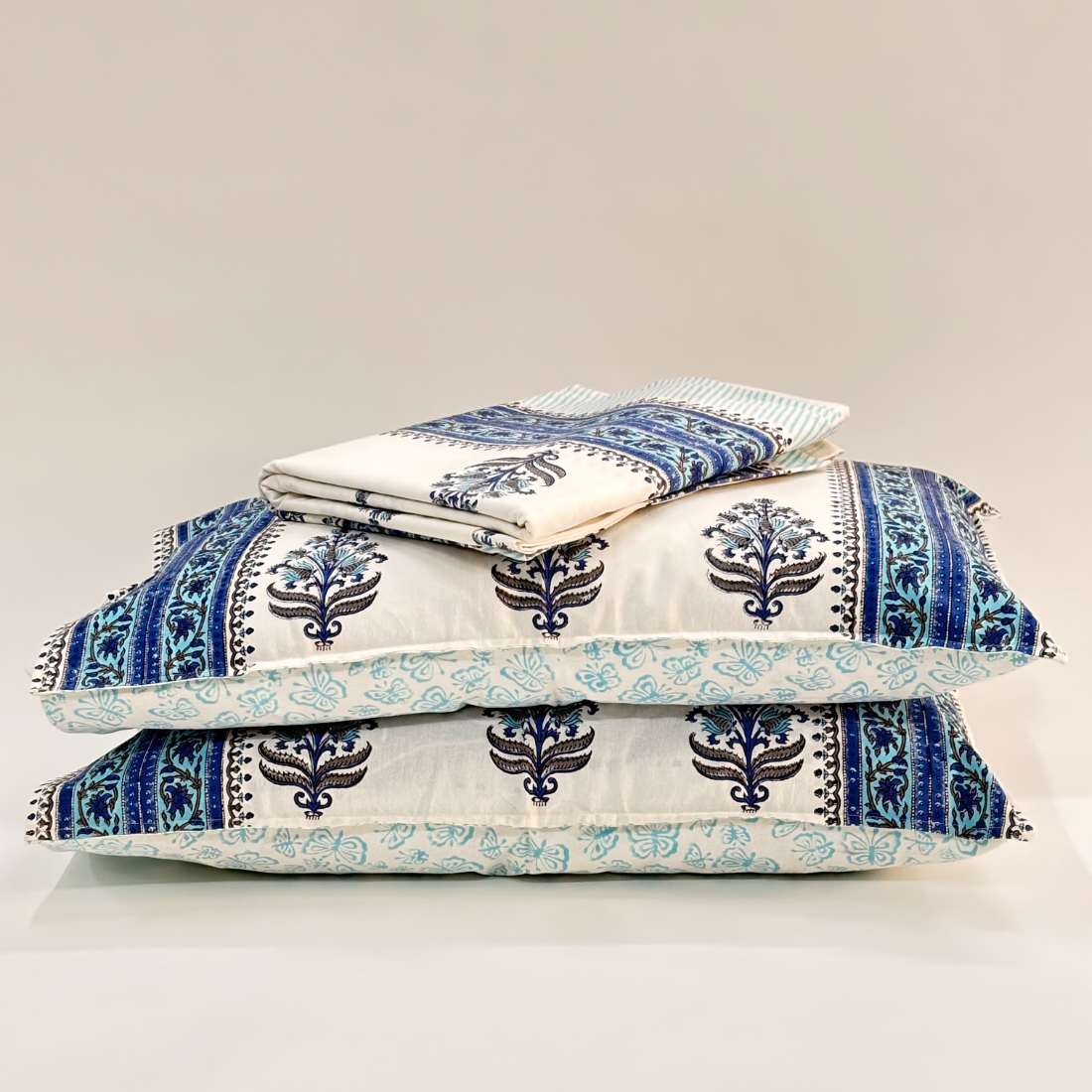 Stack of blue and white patterned pillows on a light gray background