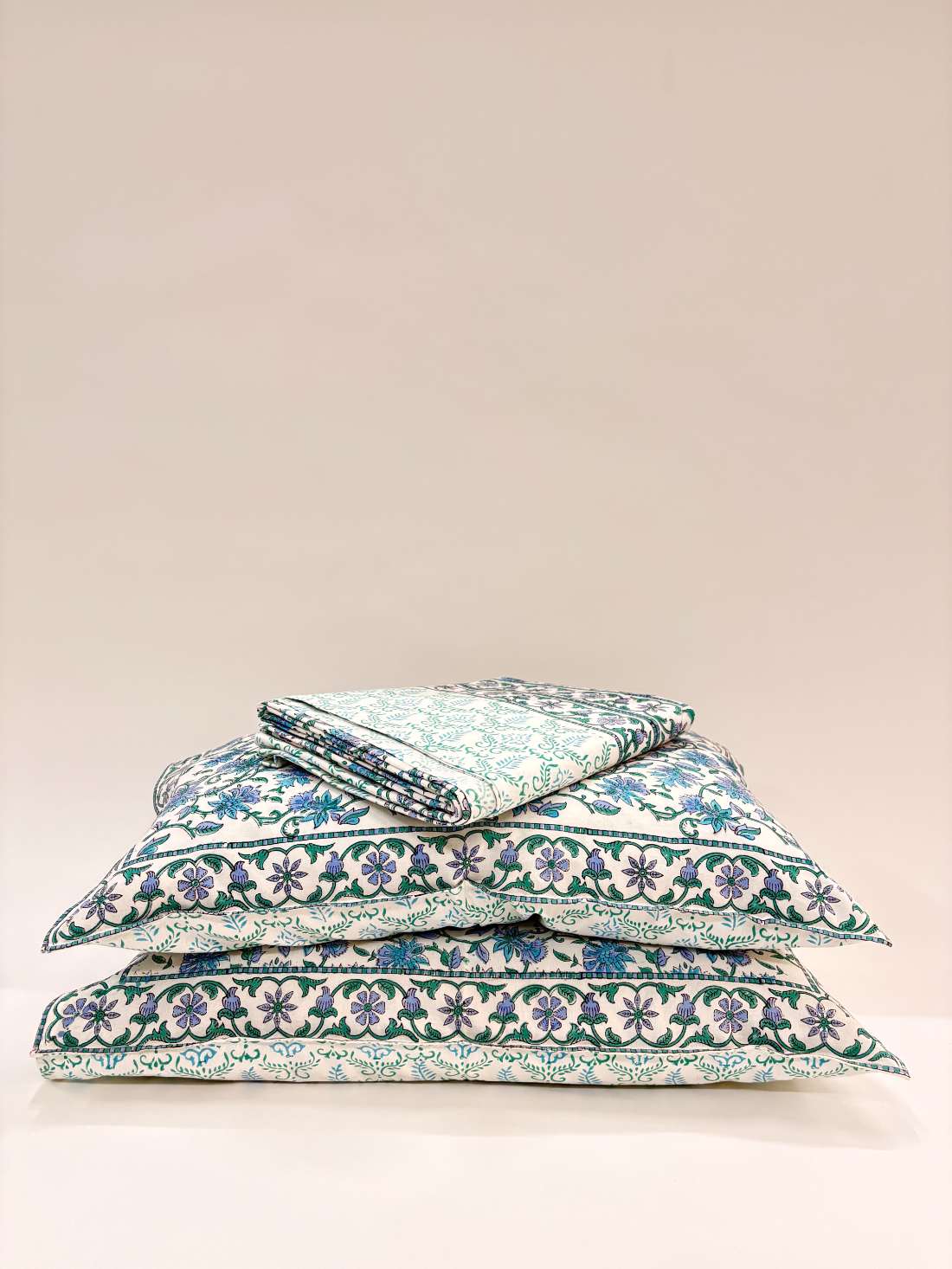 Stack of floral-patterned pillows on a beige background