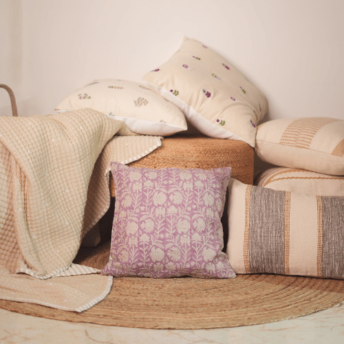 Collection of pillows and blankets on a woven surface with a neutral background