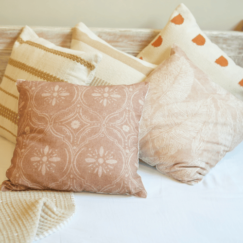 Set of patterned pillows on a bed with a neutral color palette.