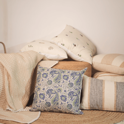 Collection of patterned pillows and blankets on a wooden surface with a neutral background
