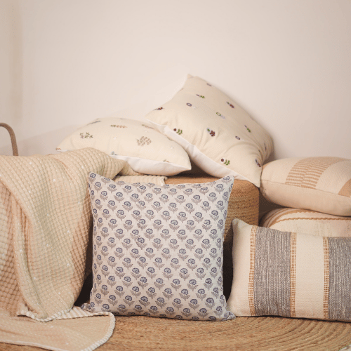 Patterned pillows and a blanket on a sofa against a neutral wall