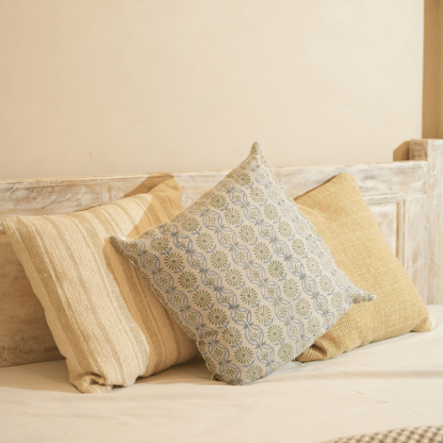 Three pillows on a bed with a neutral color scheme