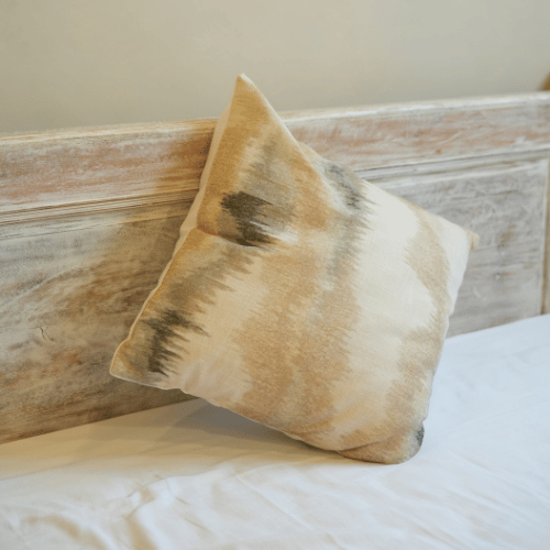 Beige pillow on a wooden headboard with white bedding