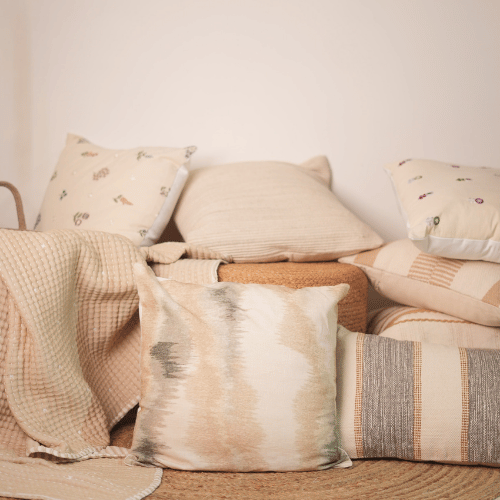 Collection of textured pillows and blankets on a sofa against a neutral wall.