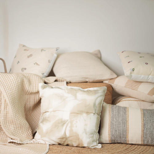 Collection of decorative pillows and blankets on a sofa against a white wall.