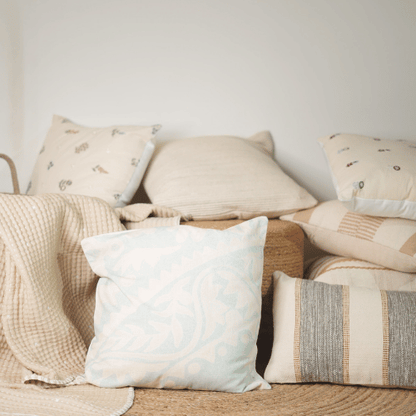 Collection of pillows and blankets on a sofa with a neutral color palette.