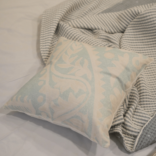Decorative pillow with floral pattern on a bed with striped bedding