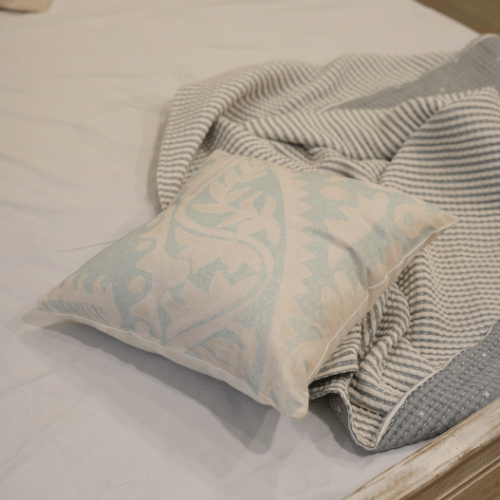 Decorative pillow with paisley pattern on a bed with striped blanket