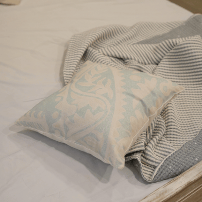 Decorative pillow with paisley pattern on a bed with striped blanket